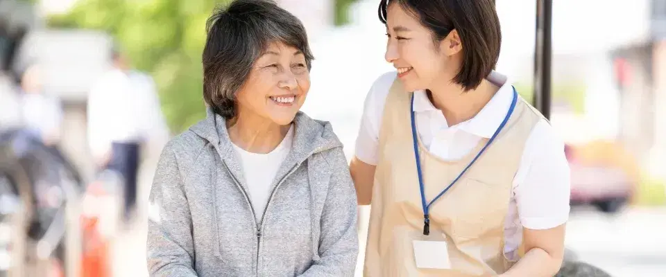笑顔で会話しながら散歩する高齢者と職員