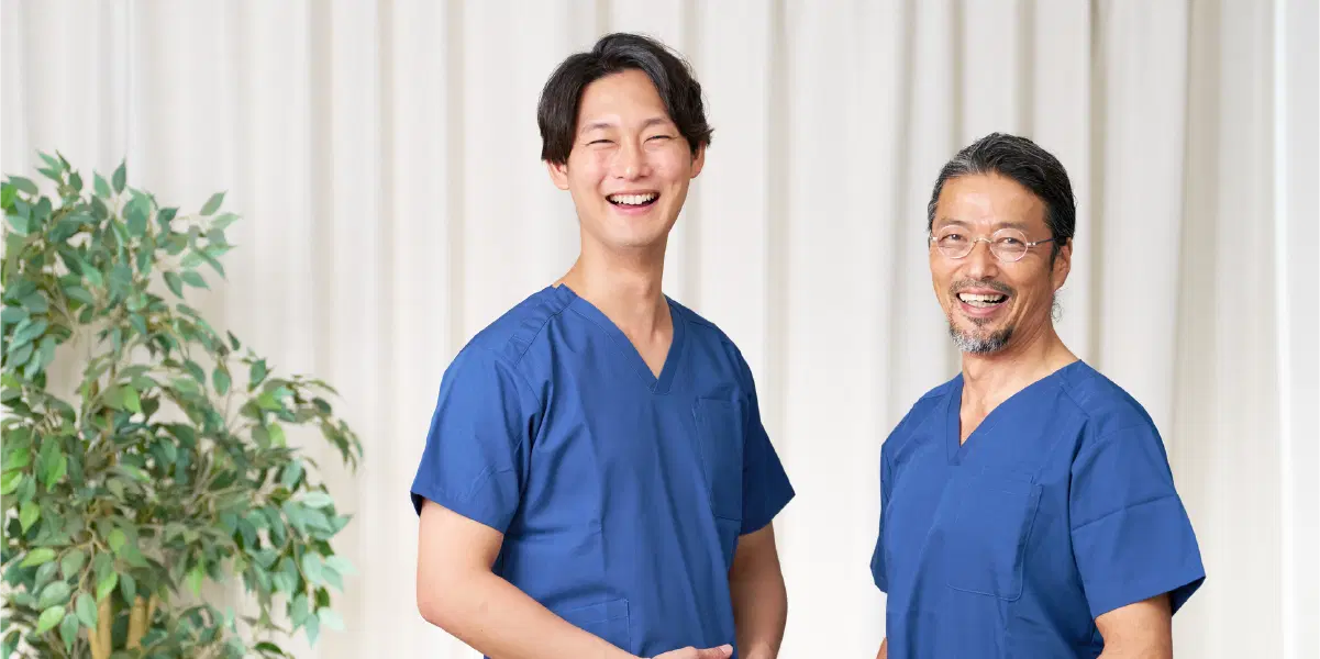青い服を来た笑顔の男性が向かい合って笑顔でこちらを見ている