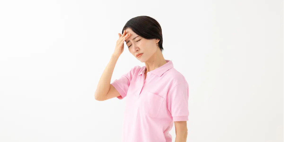 ピンクの服を着た女性が頭を抑えている