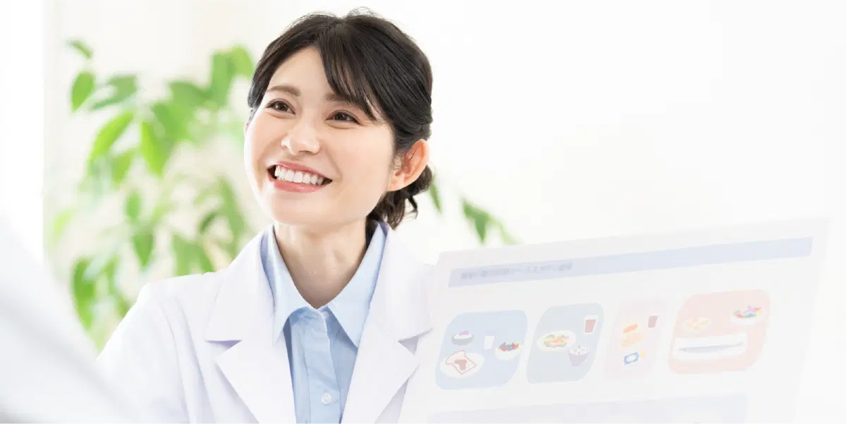白衣を着て、笑顔で説明している女性