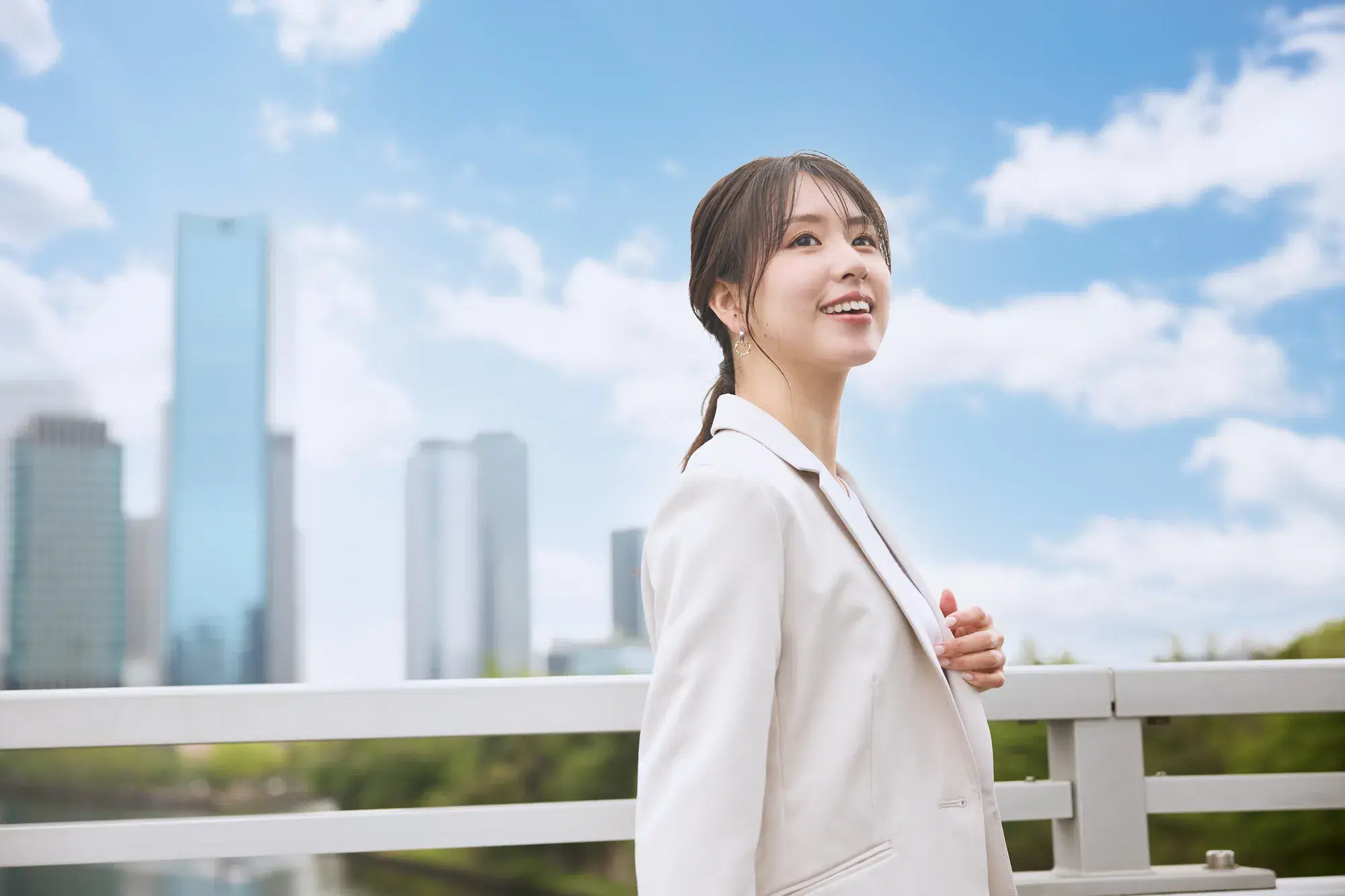 白いスーツを着た女性と背景に高いビル