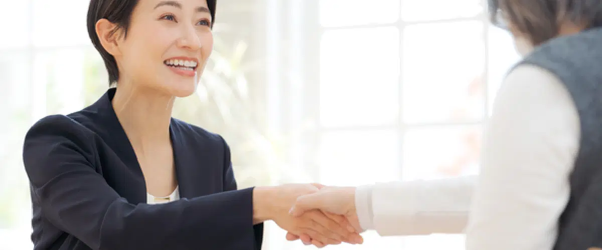 高齢者と握手するスーツの女性