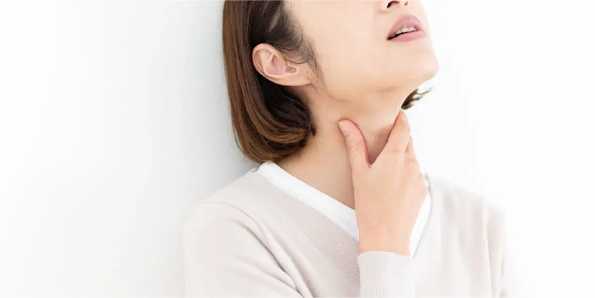 上を向き喉元に手を添える女性