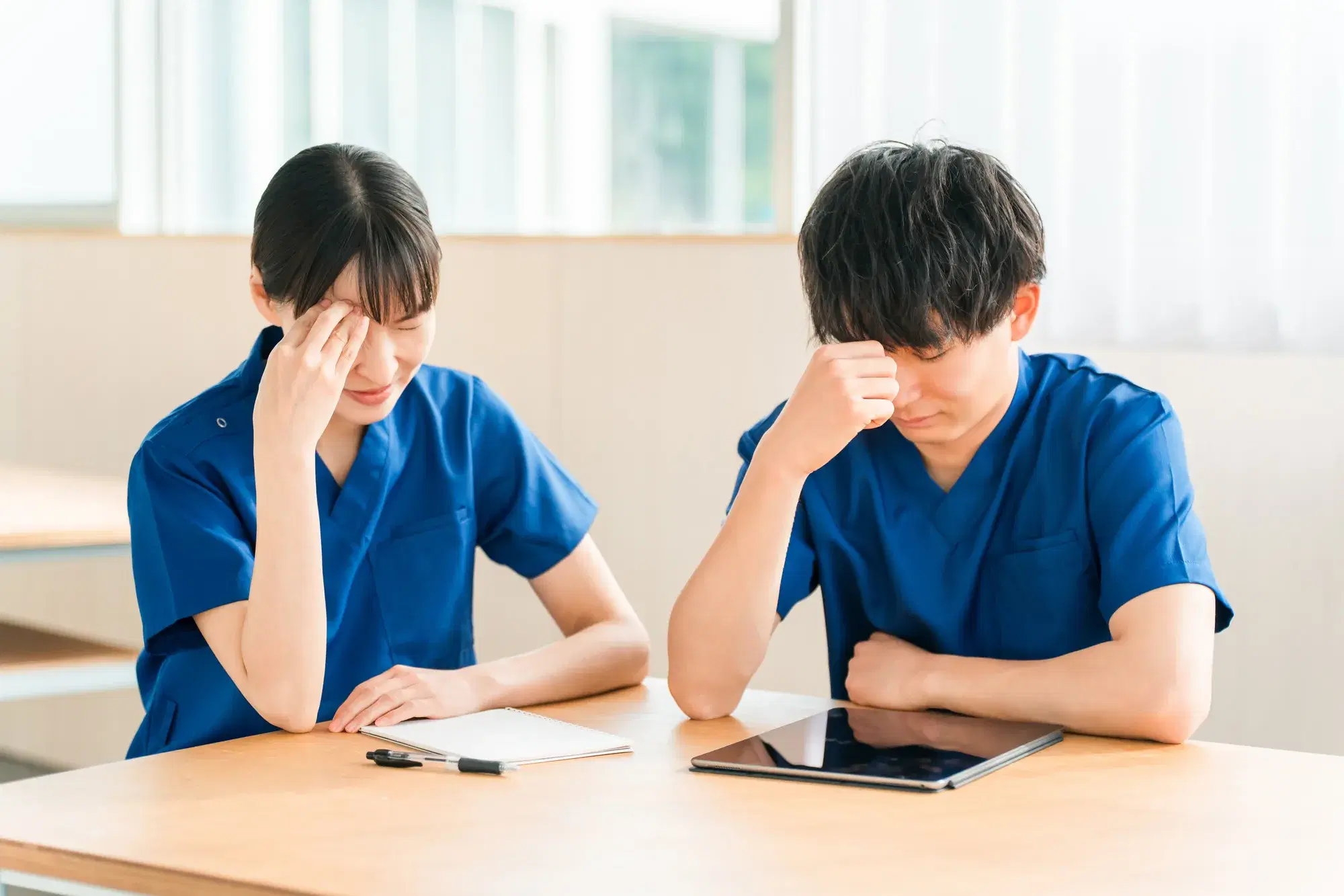 青い服を着た男女が頭に手を当てて悩む