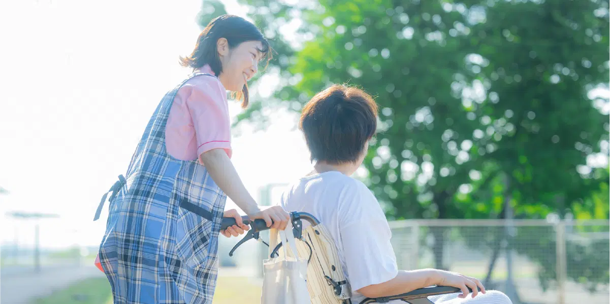 車椅子の男性を押す女性