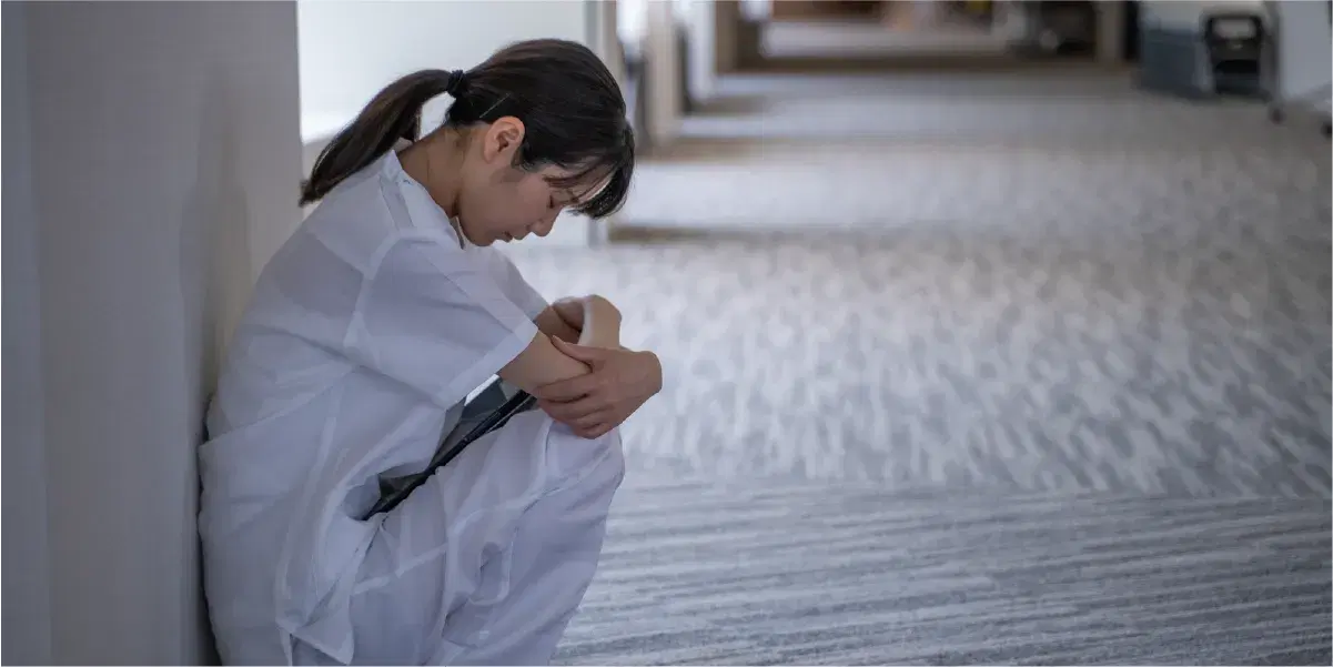 膝を抱えて蹲る落ち込んだ様子の看護職員女性