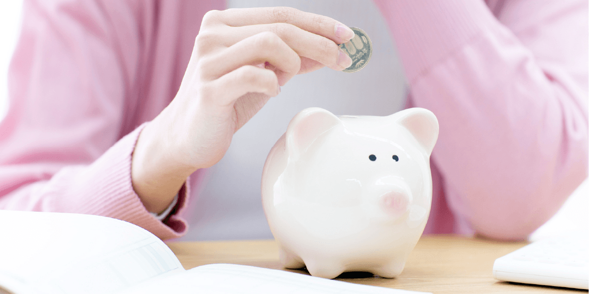 豚の貯金箱にお金を入れようとしている