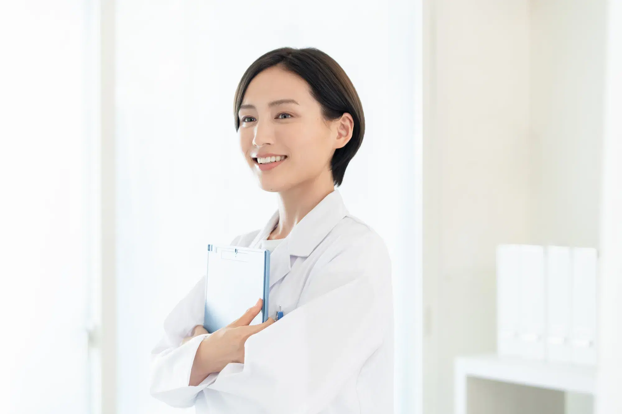 バインダーを両手で抱えている白衣を着た女性