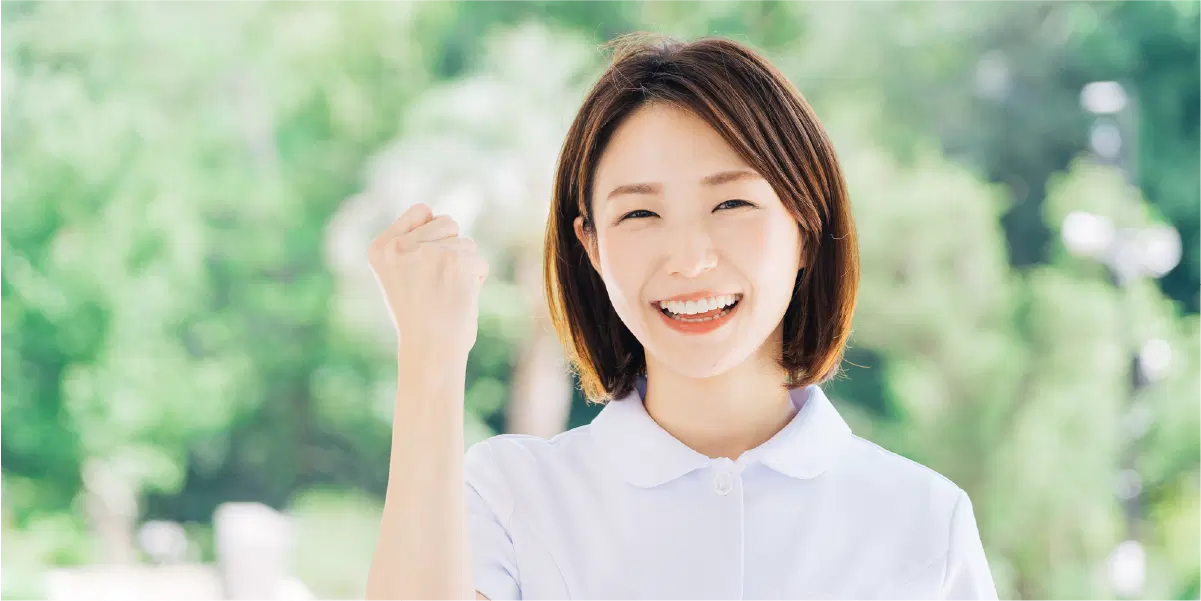 森を背景に女性が左手でガッツポーズしている