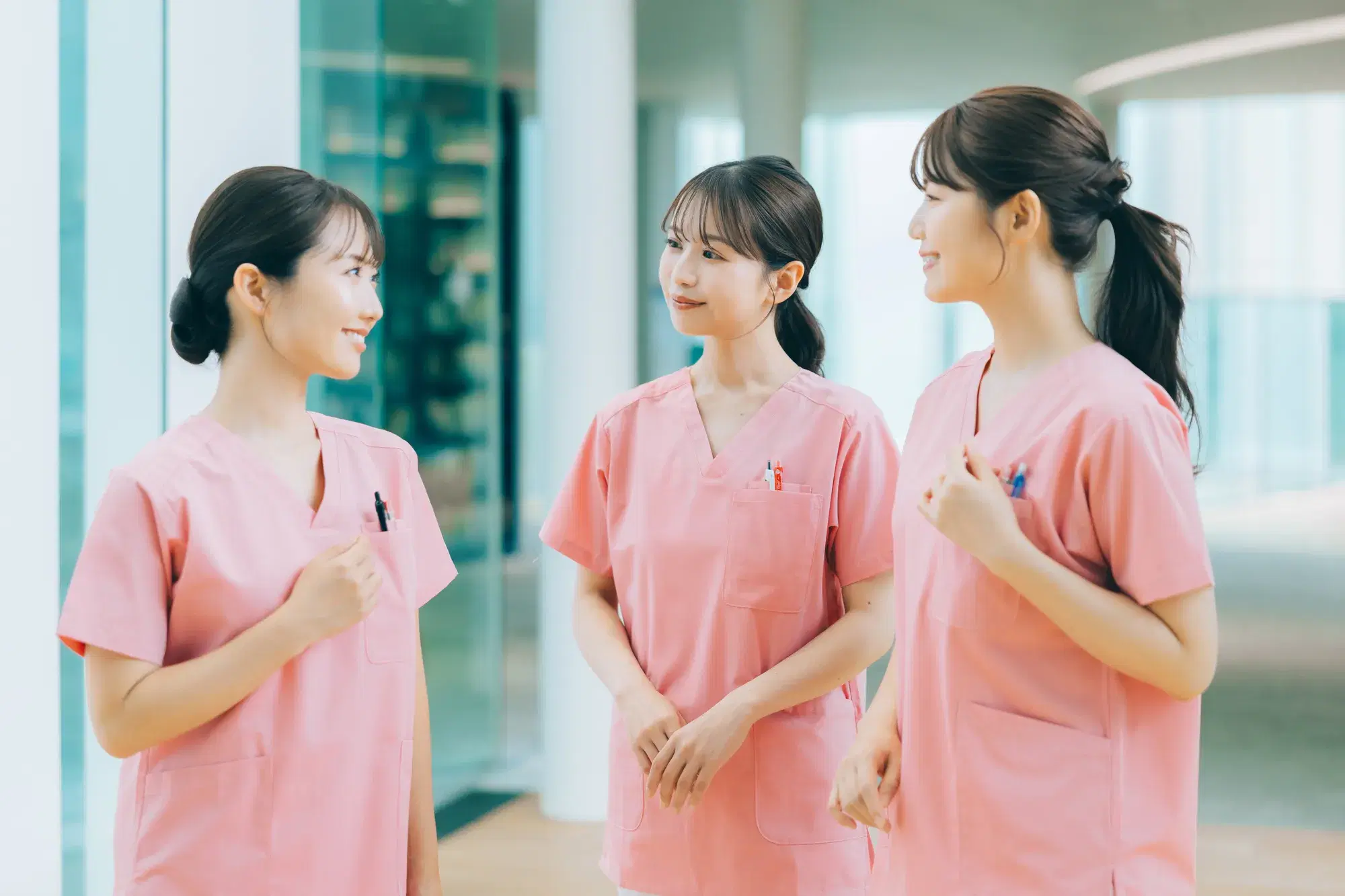 ピンク色の服を着た複数の女性が廊下で会話