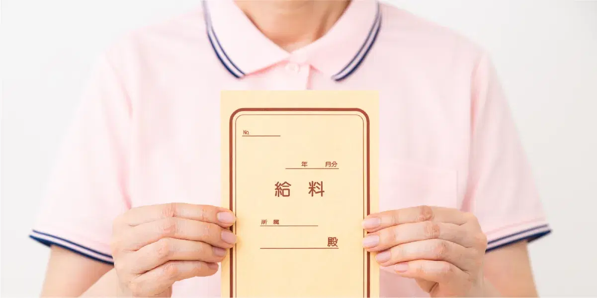 給料と書かれた封筒を持つピンクのポロシャツを着た人