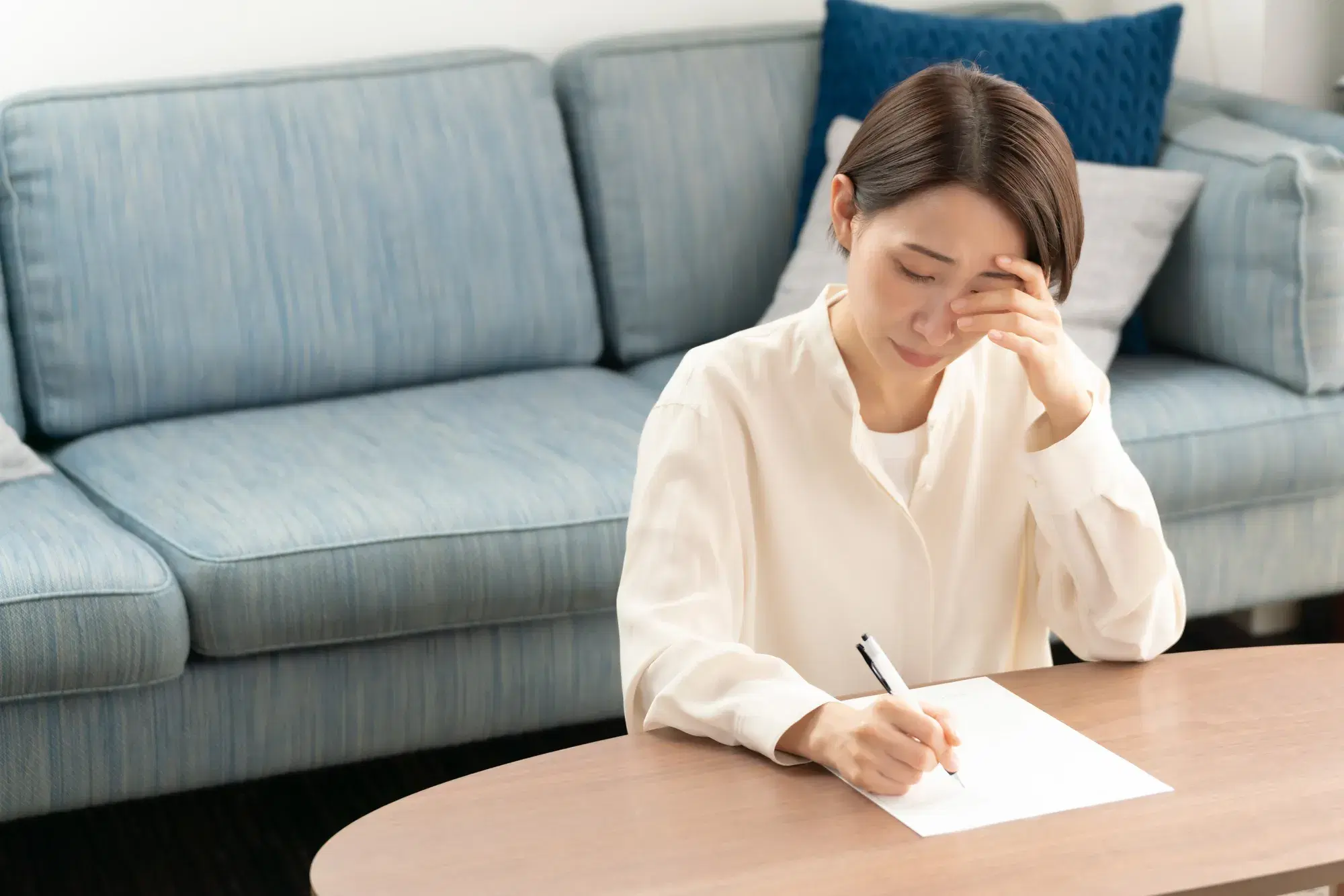 頭を抱えながら書類を記入する女性