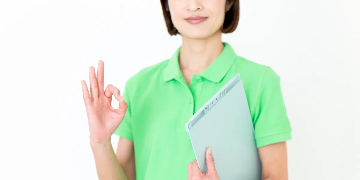 指で丸を作り黄緑色の服を着ている女性