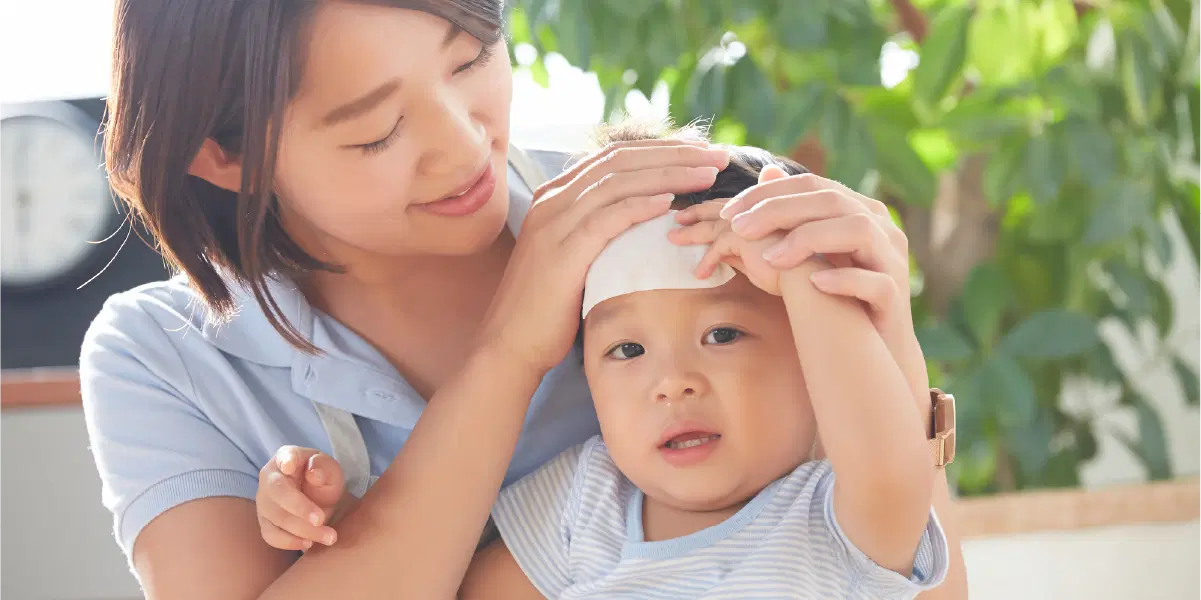 母親と冷却シートをおでこにつけた幼児