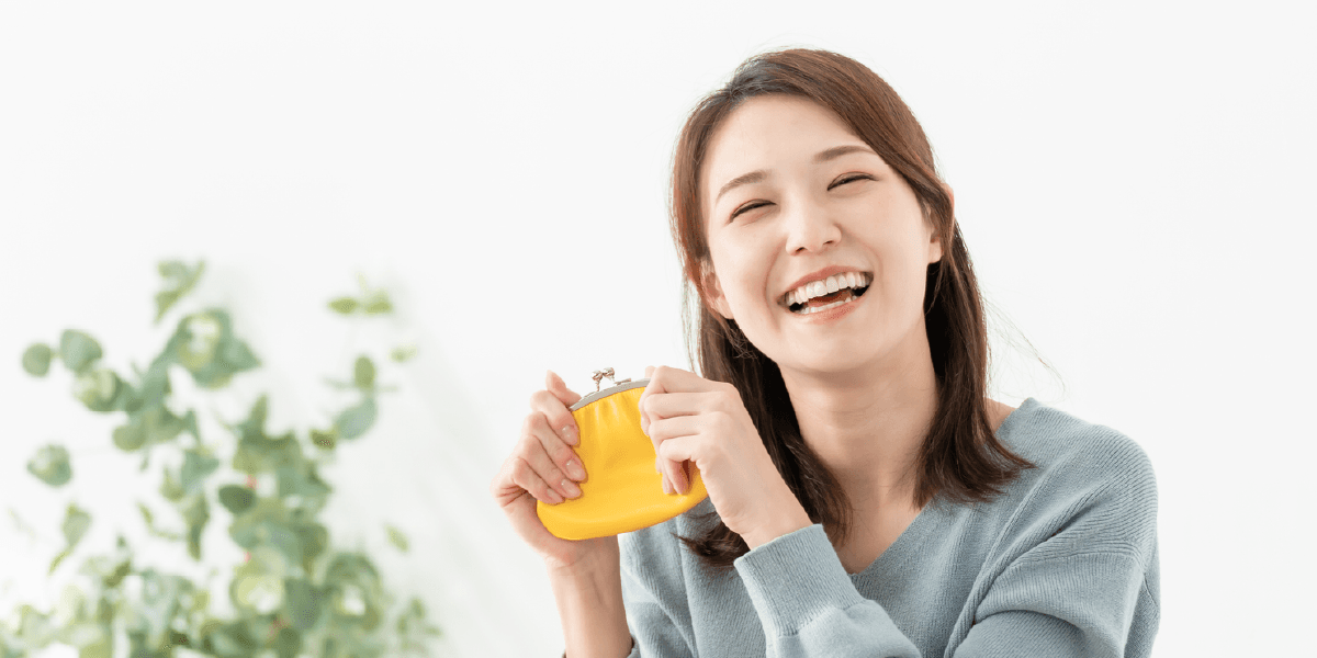 黄色いがま口財布を持ち笑っている女性
