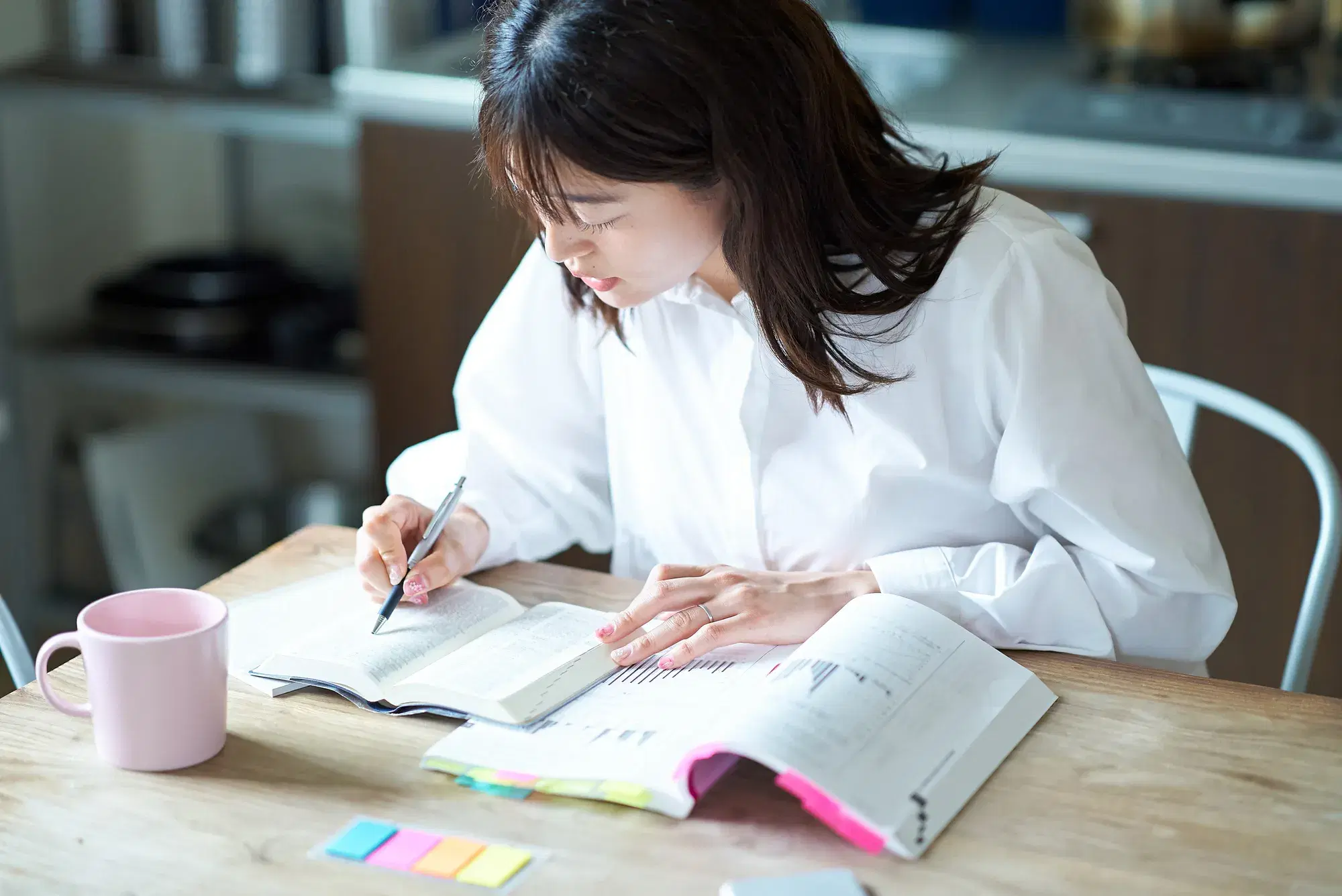 白い服を着た女性が勉強をしている。
