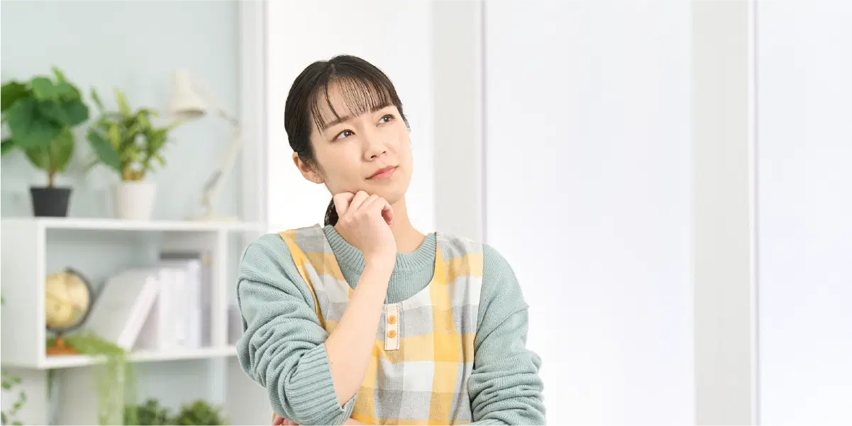 首を傾げ考える様子のエプロンを付けた女性