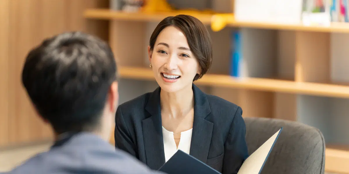 バインダーを持ち男性に語り掛ける女性
