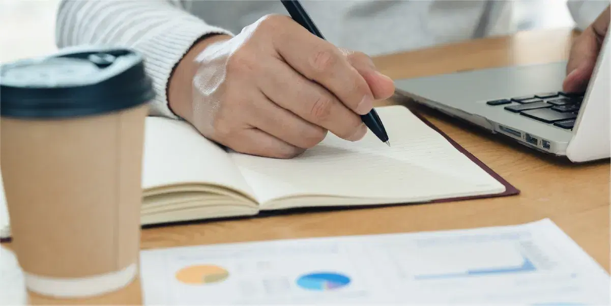 パソコンと資料を確認しながら勉強をする人