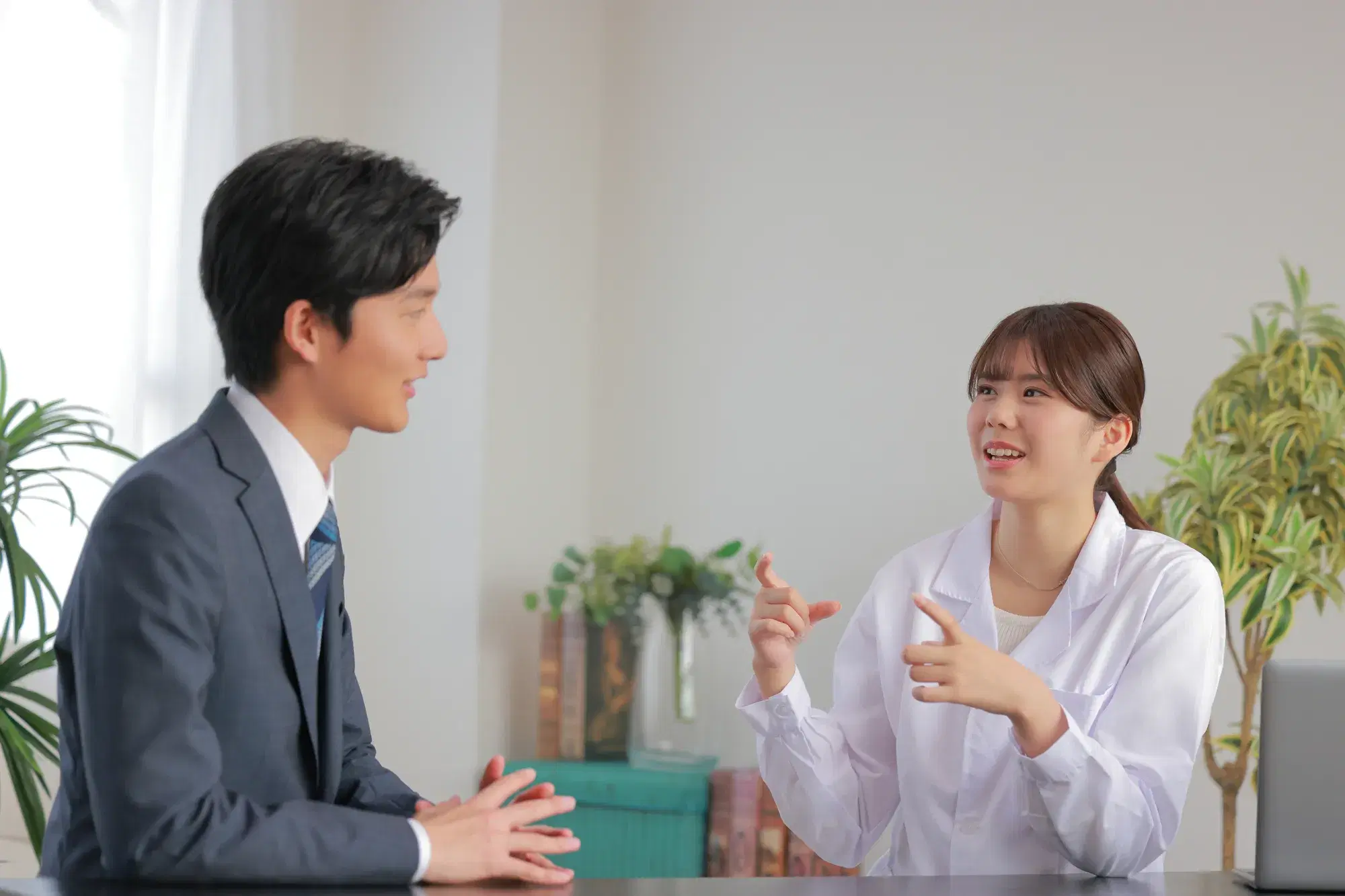 白衣を着た女性が灰色の服を着た男性に説明