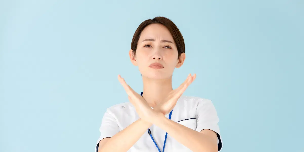 胸の前で腕を交差させ、バツをつくる女性