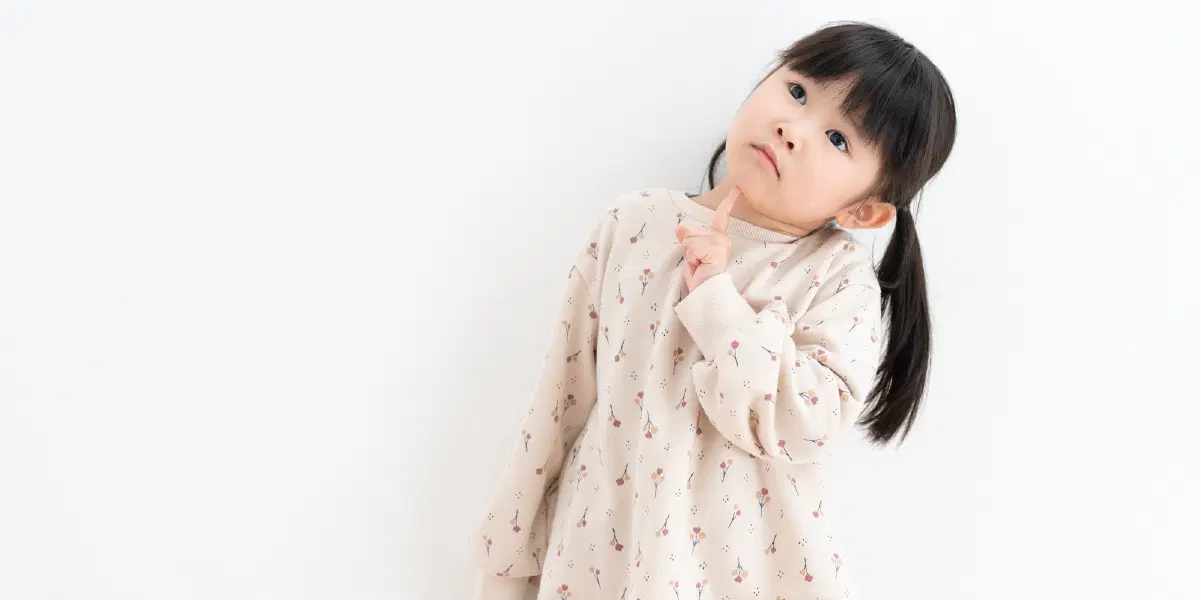 首をかしげて考える様子の幼児の女の子