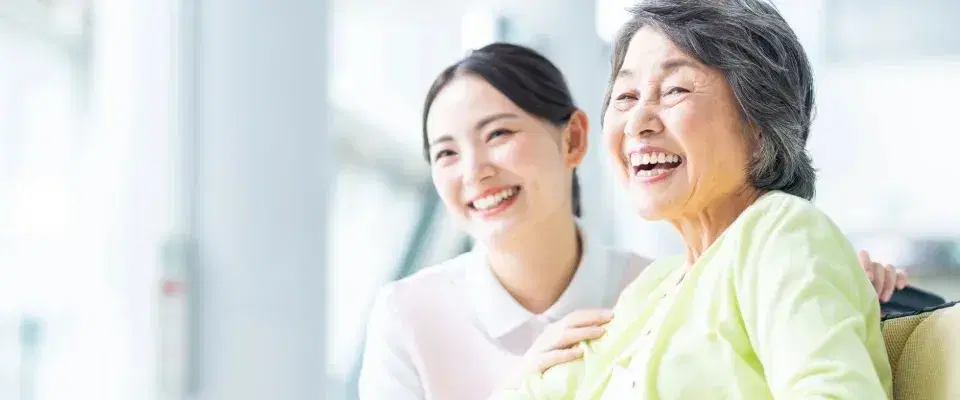 笑顔で遠くを見つめる高齢女性と職員