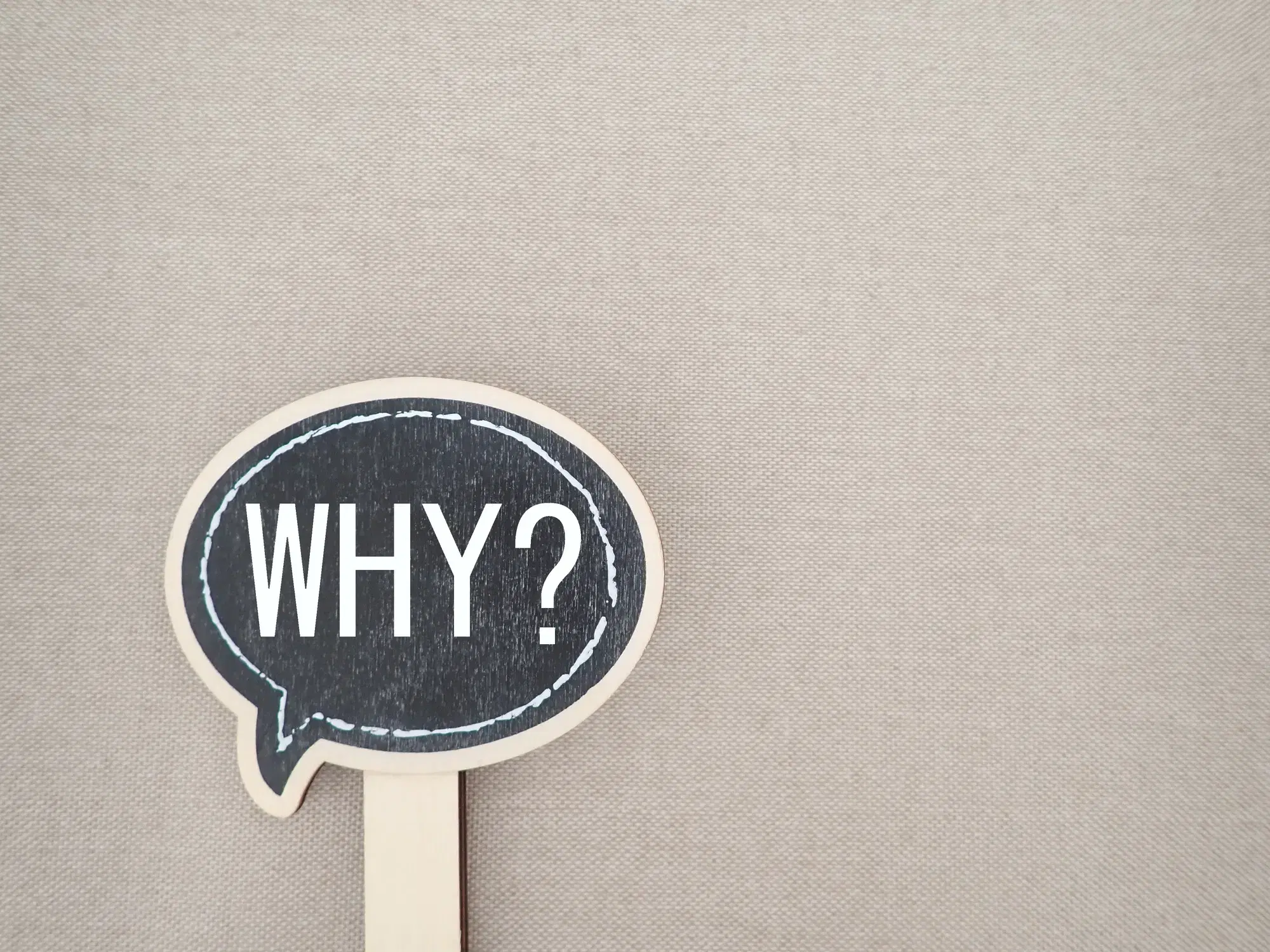 「WHY?」と書かれた吹き出し型のプレートが写っている。