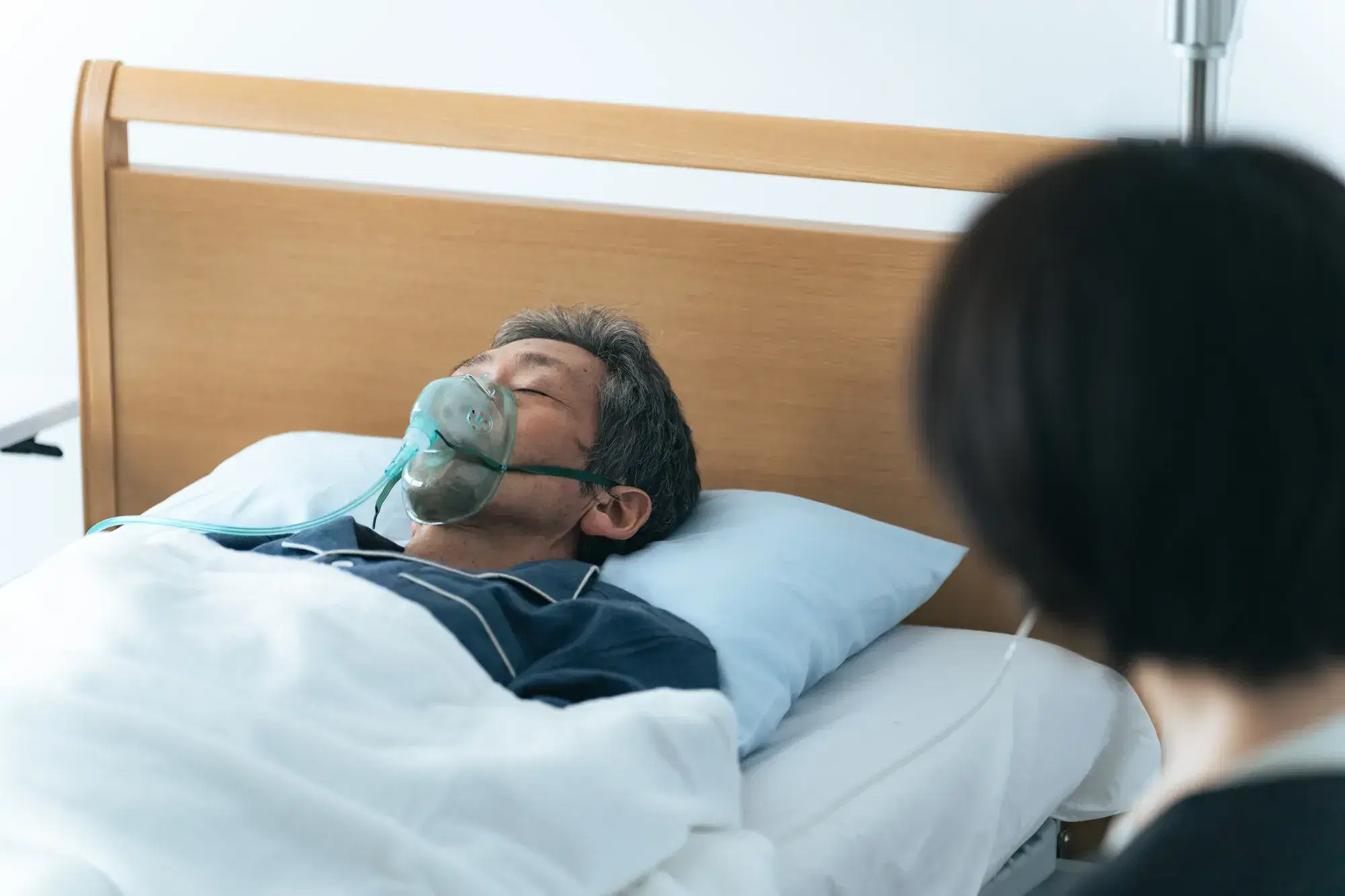 白髪の黒い服を着た男性が呼吸器をつけながら眠っている