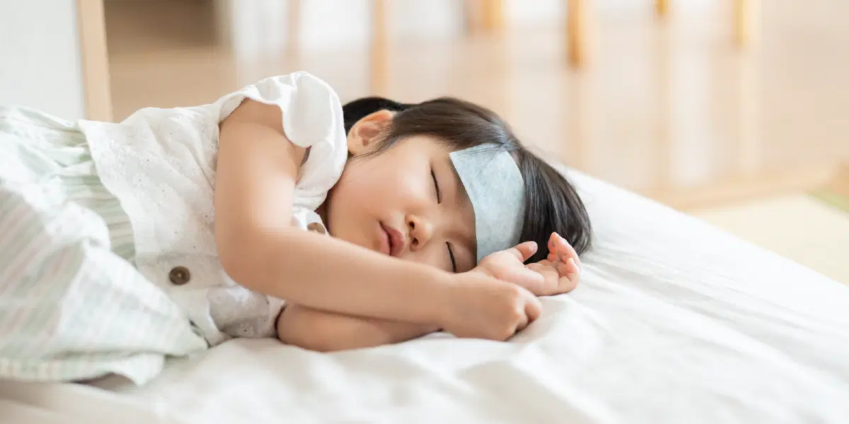 冷却シートをおでこにつけて眠る幼児