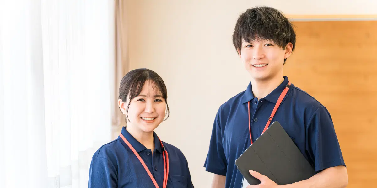 バインダーを持ち赤いストラップをかけた青い服を着た男女