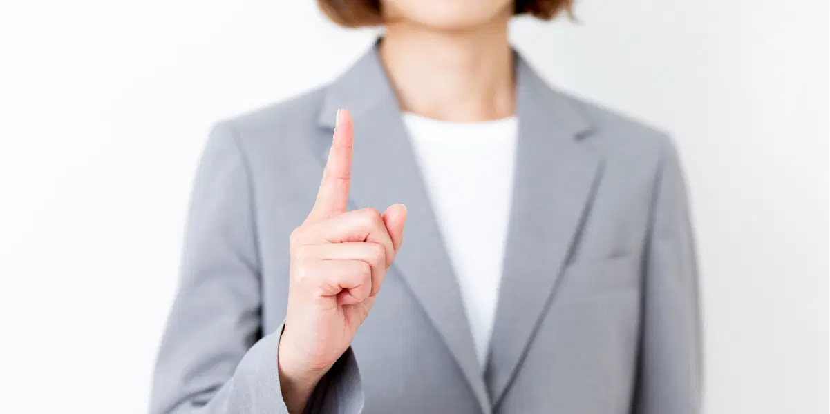 人差し指を立てるスーツを着た女性