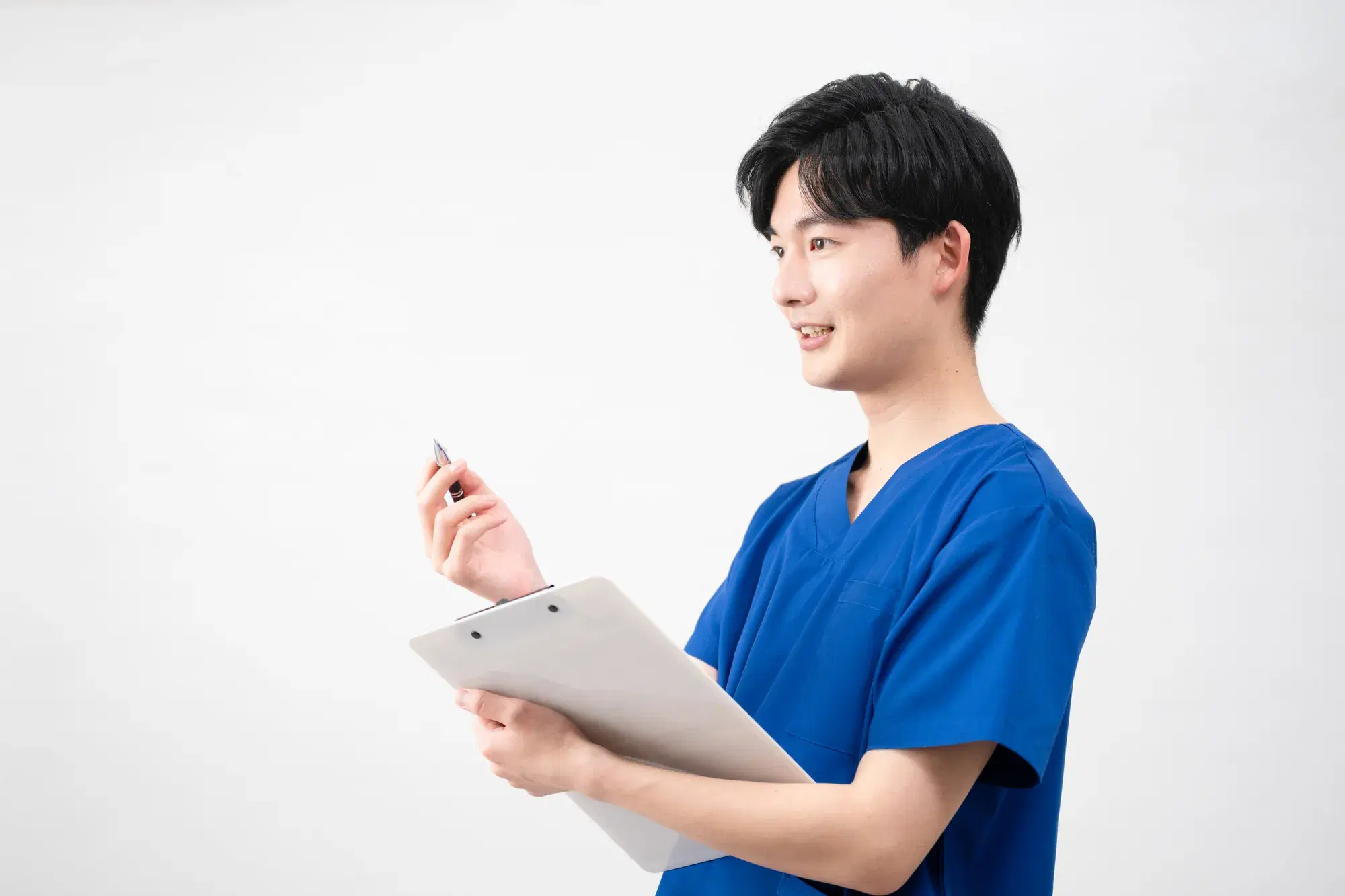 青いスクラブを着た男性の医療従事者がバインダーとペンを持って説明している。