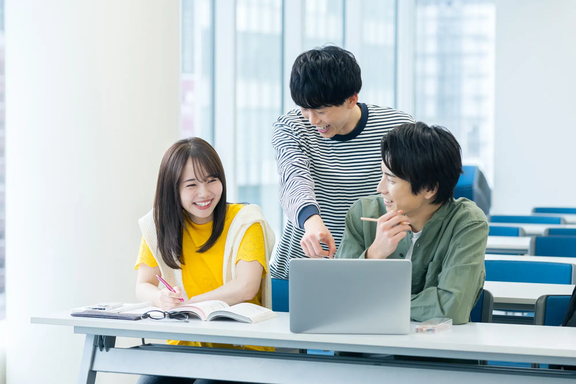 PCを見ながら笑う男女三人組