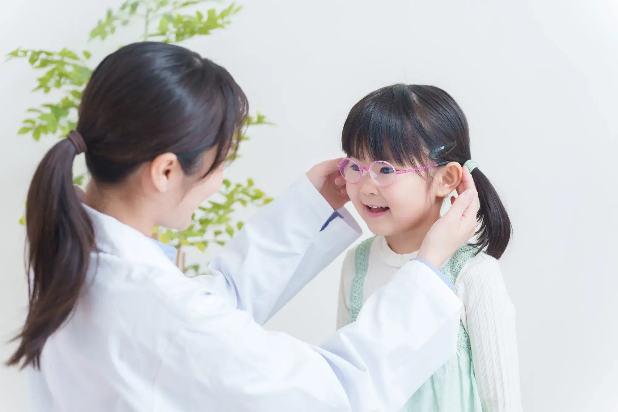 女性の人が女の子にピンクの眼鏡をかけている様子
