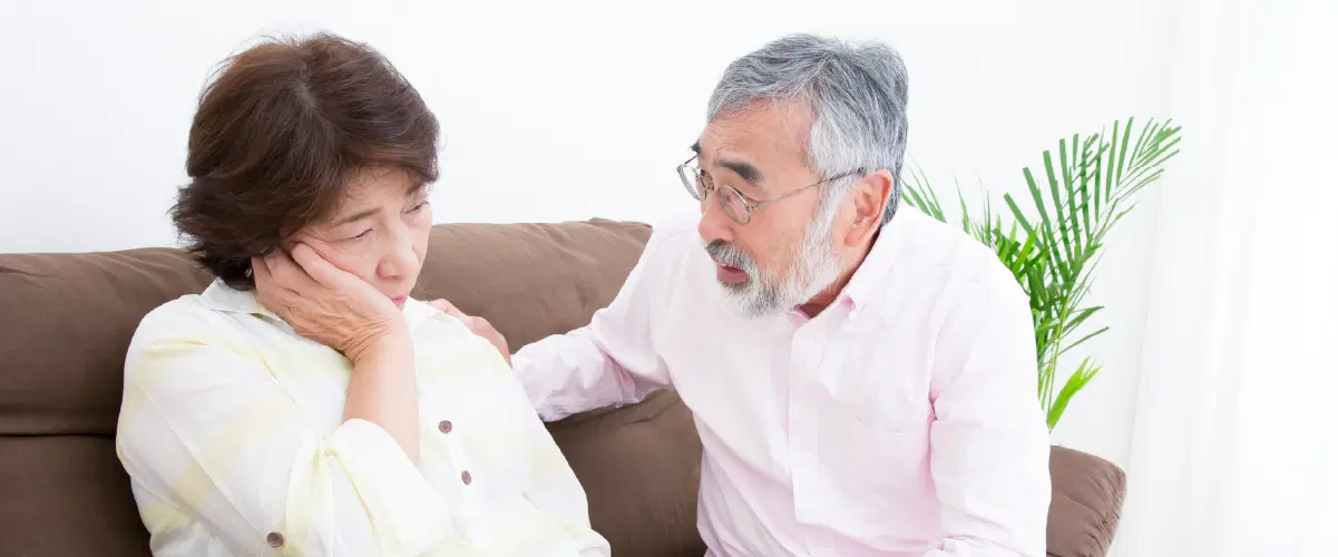 ソファーで複雑な表情している女性と話をしている男性