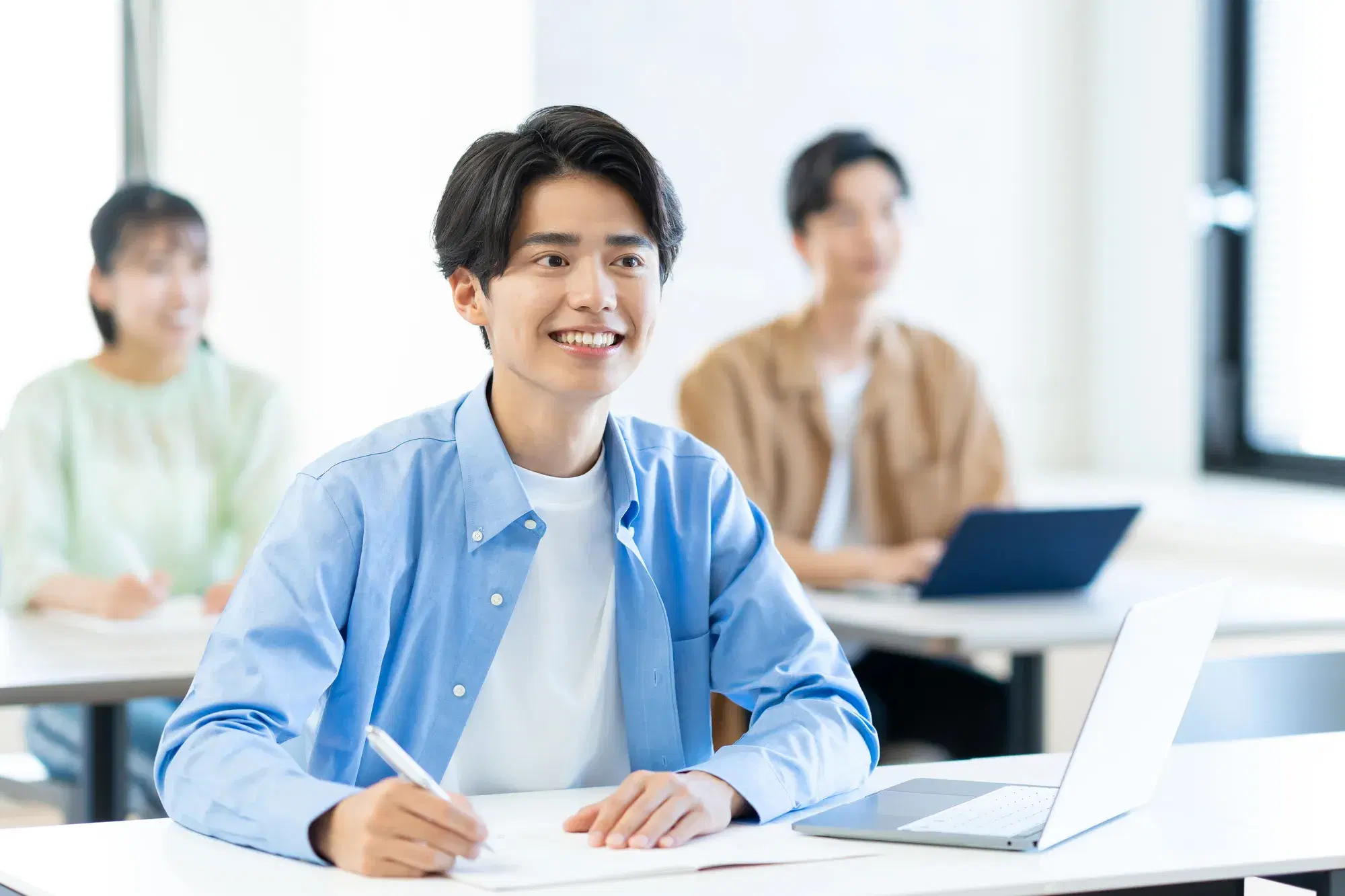 青いシャツの青年が笑顔で板書している