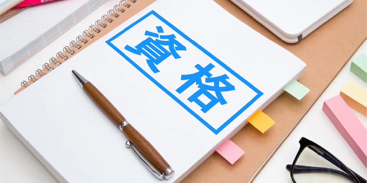青い字で資格と書かれた冊子に付箋紙がいくつかはさまり、上にペンが置いてある。