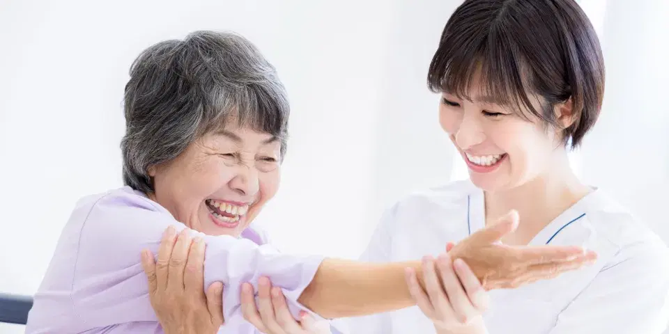 リハビリをする高齢女性とその介助を行う女性
