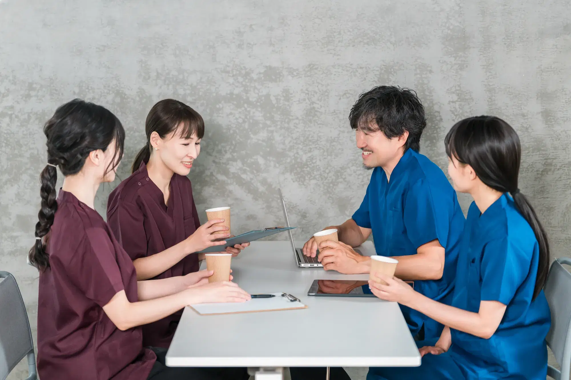 赤茶色の服を着た2人の看護師と青い服を着た2人の男女