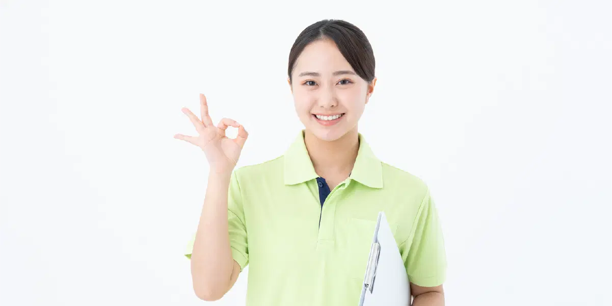 黄緑色の服を着て指で丸を作る女性