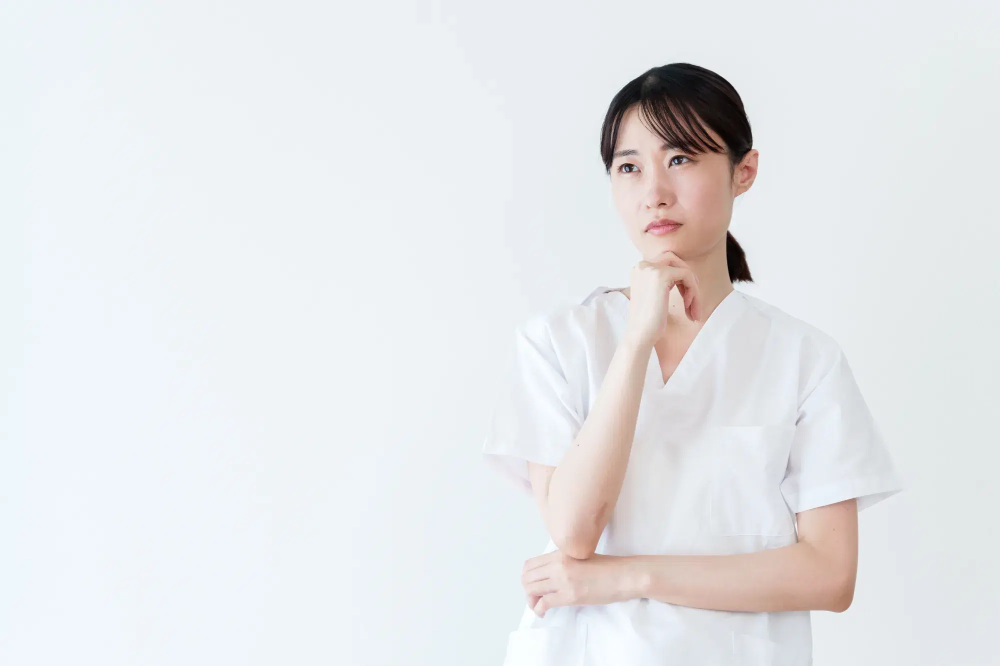 白衣を着た女性が首をかしげている