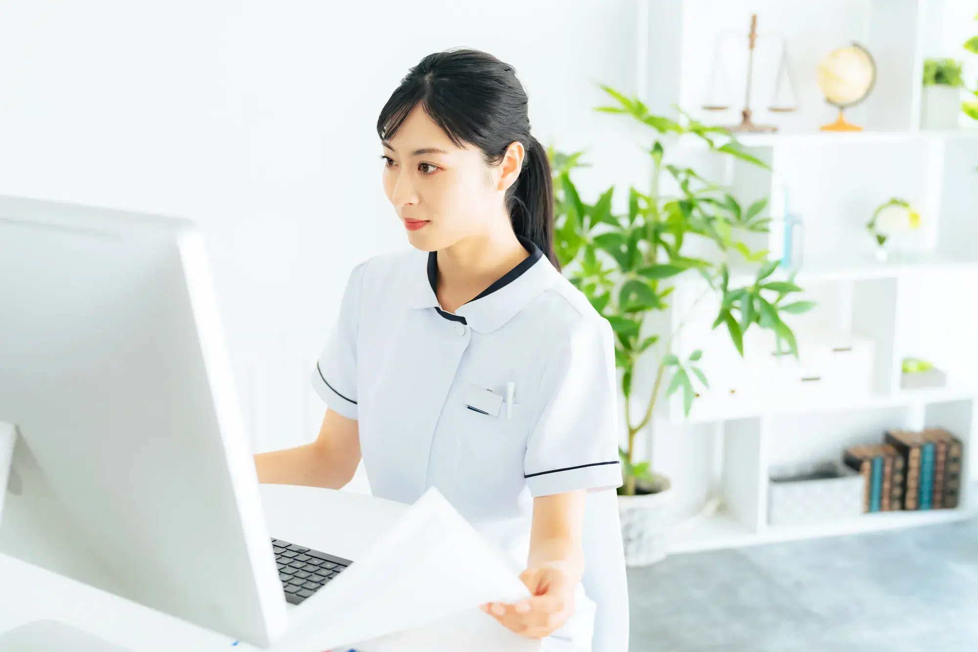 白い服を着た女性がパソコンを操作