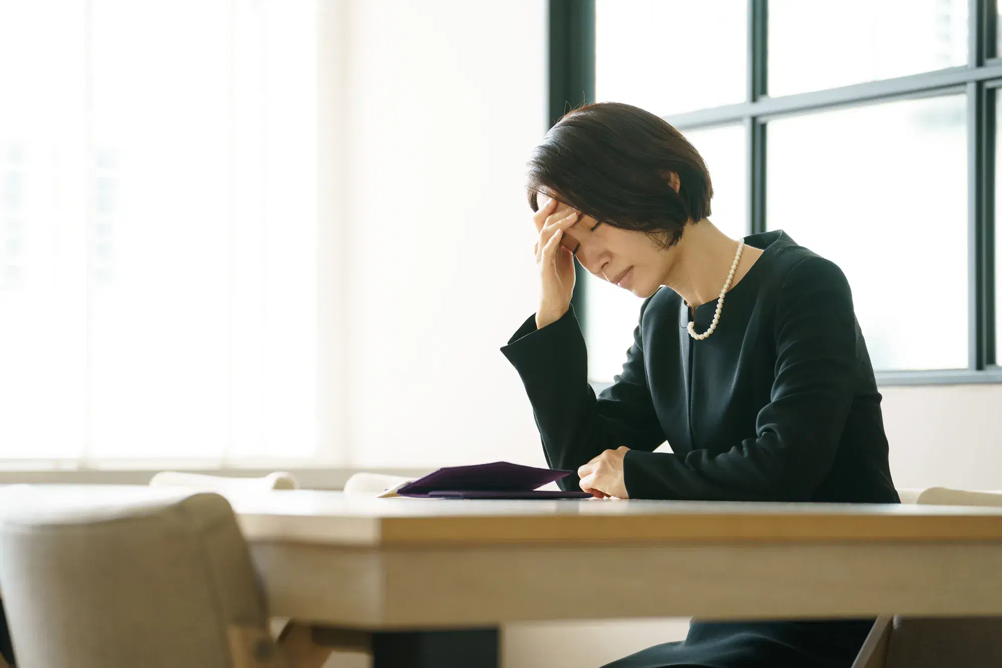 黒い服を着た女性が頭を抱えている