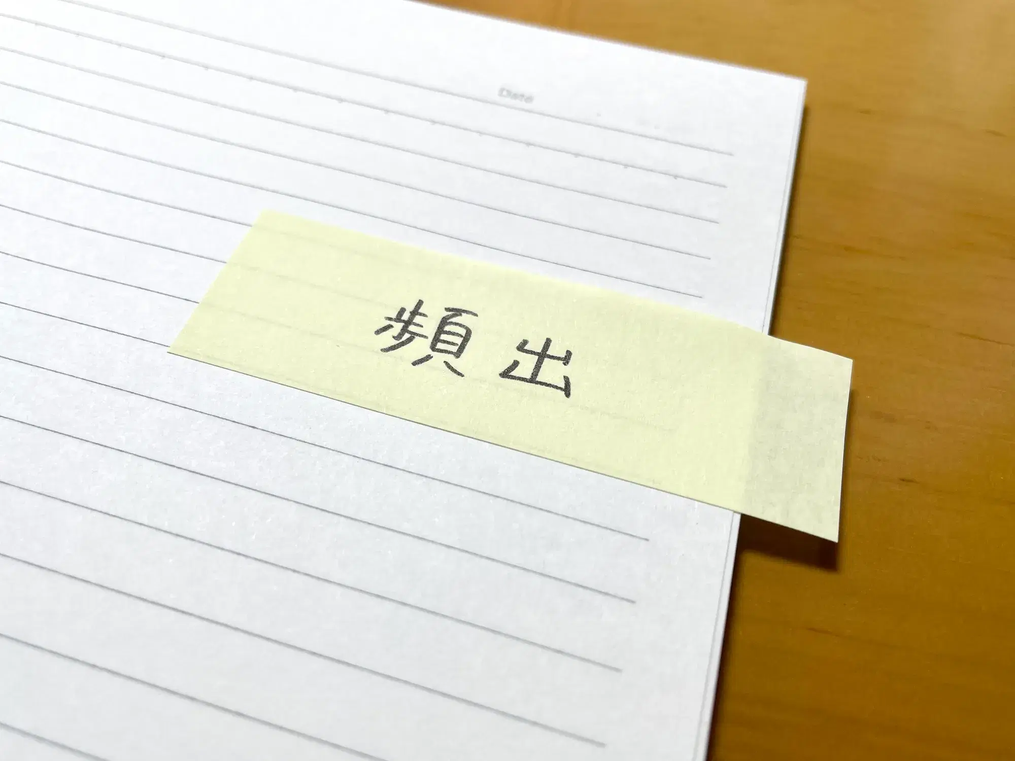 「頻出」と書かれた黄色の付箋が貼られたノートが写っている。