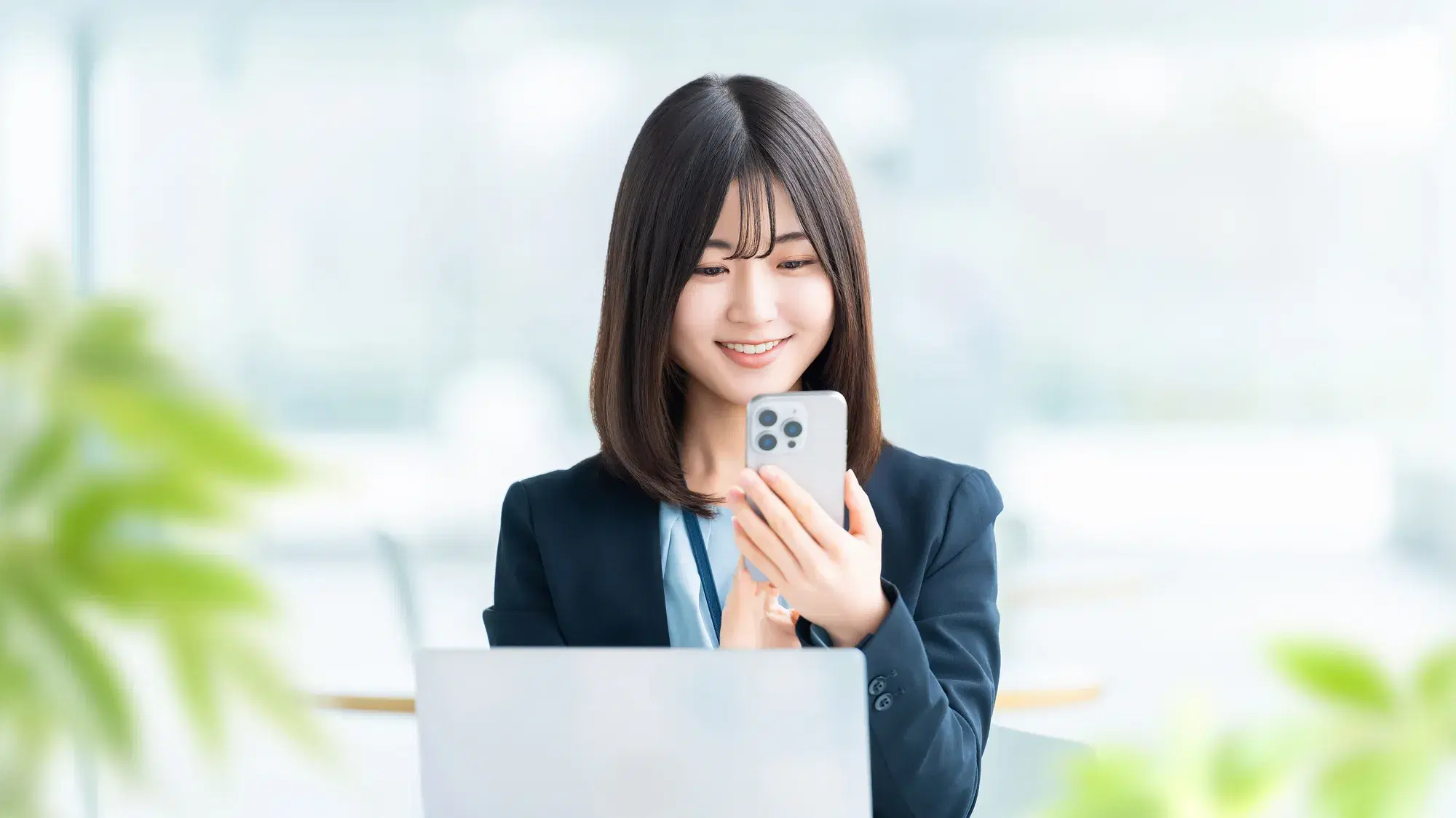 黒いスーツを着た女性がスマホを操作