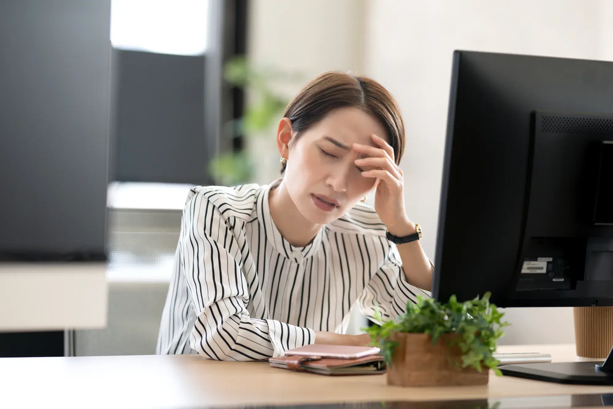 PCの前で頭を抱える女性