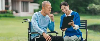 介護士さんが高齢者にクリップボードを見せている
