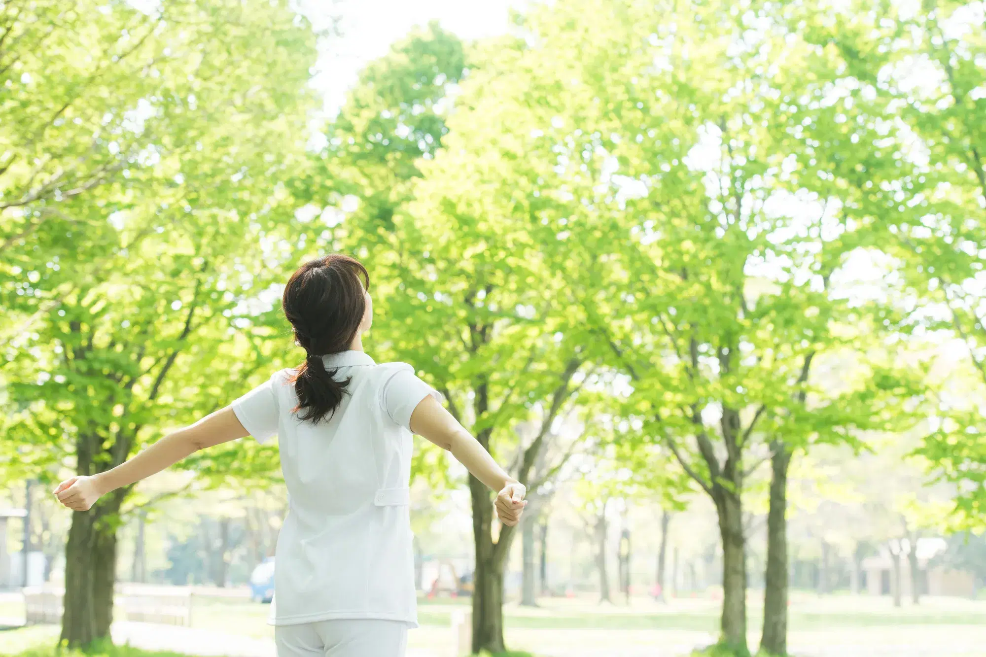 木の多い場所で看護師が腕を後ろにもっていっている。