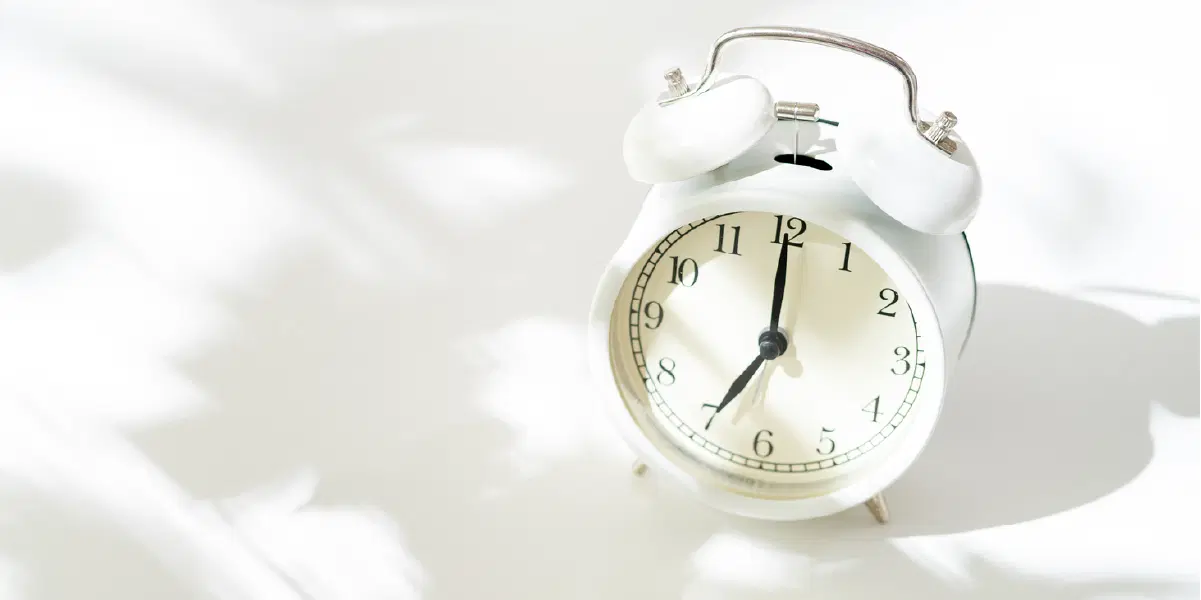 日の指す白い部屋に時計が置かれでいる